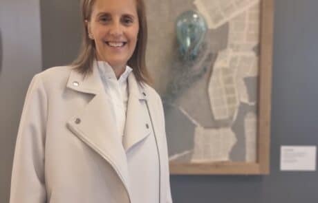 Maria Helgars framför konstverk skapat av återbrukat material på Returpunkten i Solna.